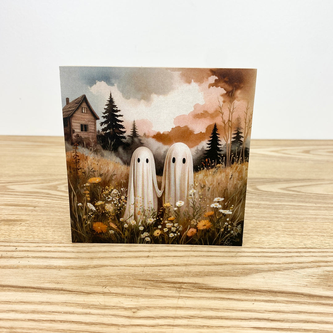Two ghosts standing in a field with trees and a house in the background on a wooden surface.