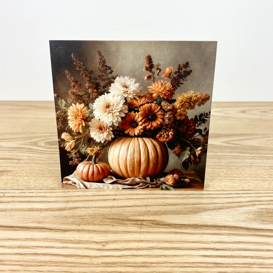 Block with autumn-themed design featuring pumpkins and flowers on a wooden surface.
