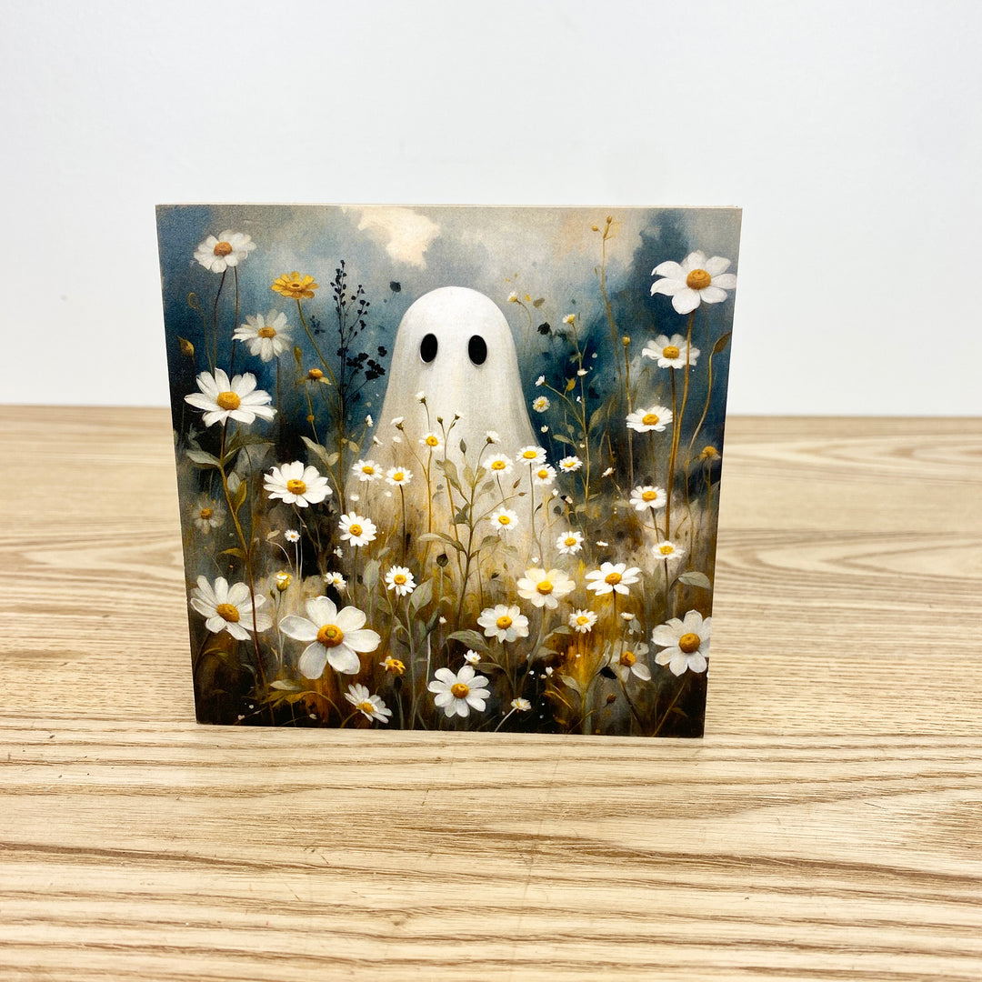 Greeting card with a ghost surrounded by flowers on a wooden surface