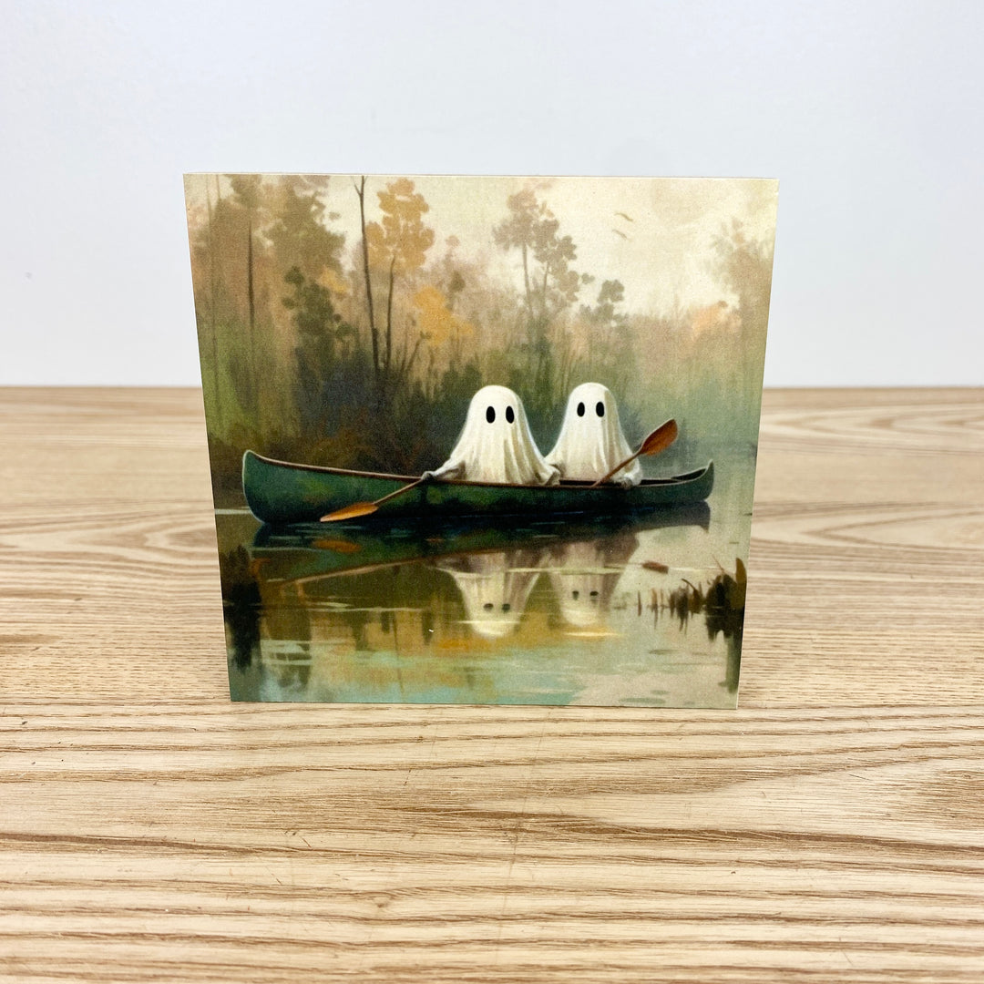 Two ghostly figures in a canoe on a lake with trees in the background
