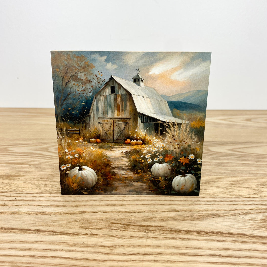 Painting of a rustic barn with pumpkins on a wooden surface