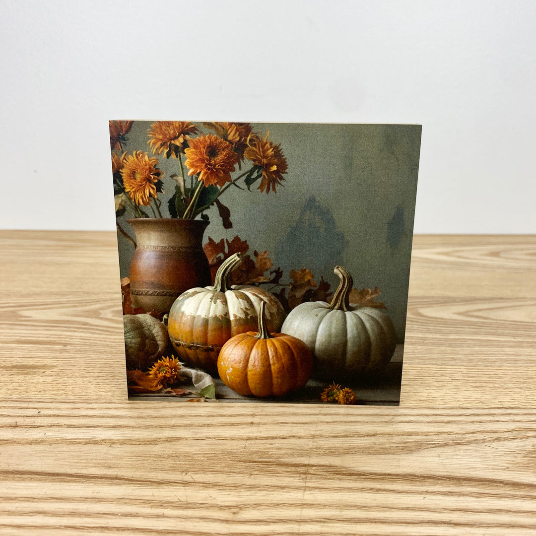 Card with pumpkins and flowers on a wooden surface