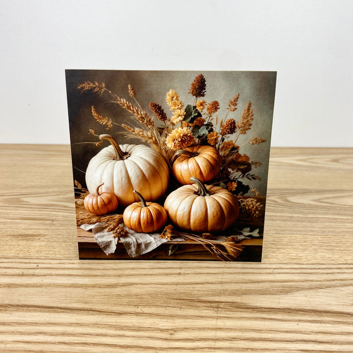 Decorative card with pumpkins and autumn foliage on a wooden surface