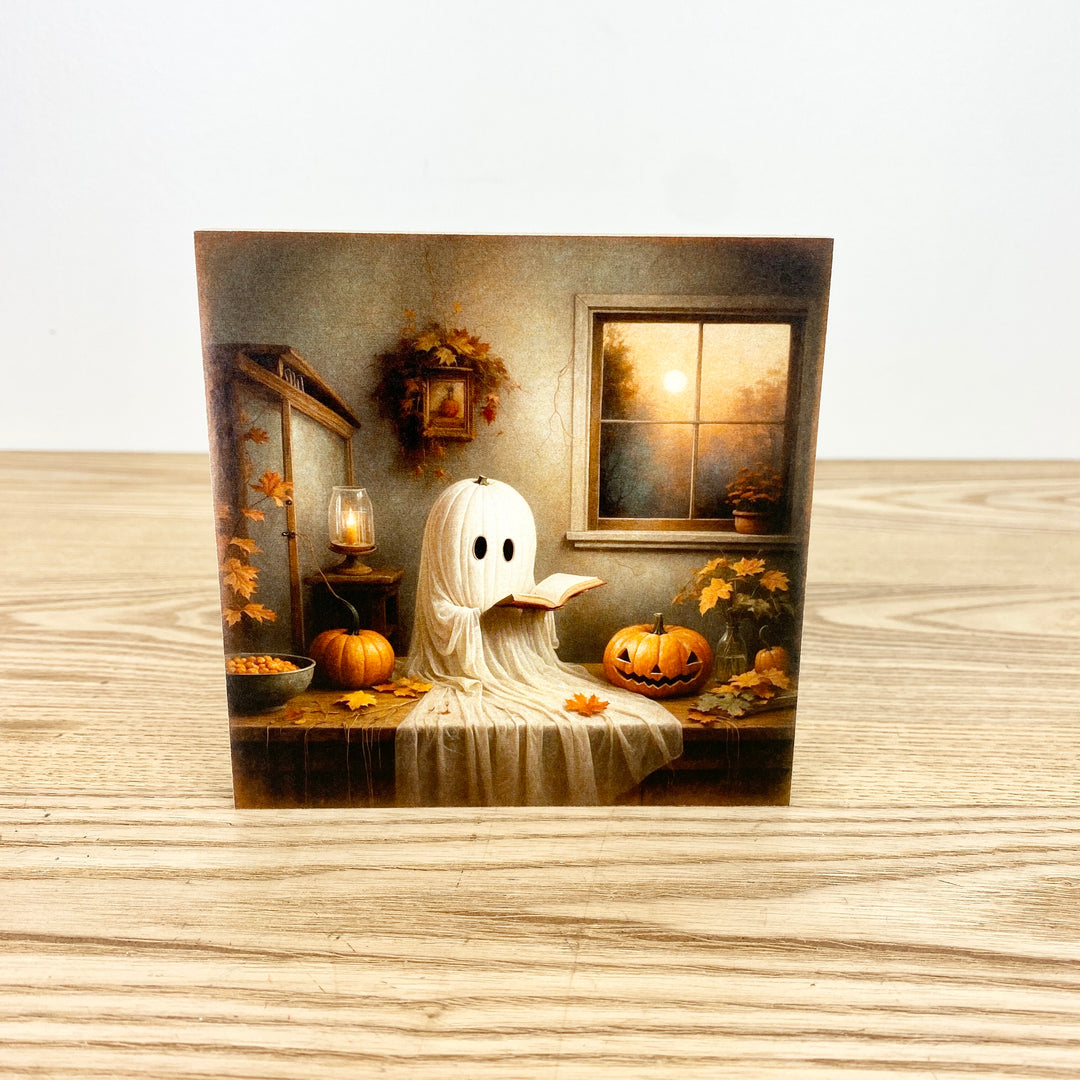 Halloween-themed greeting card with a ghost and pumpkins on a wooden surface