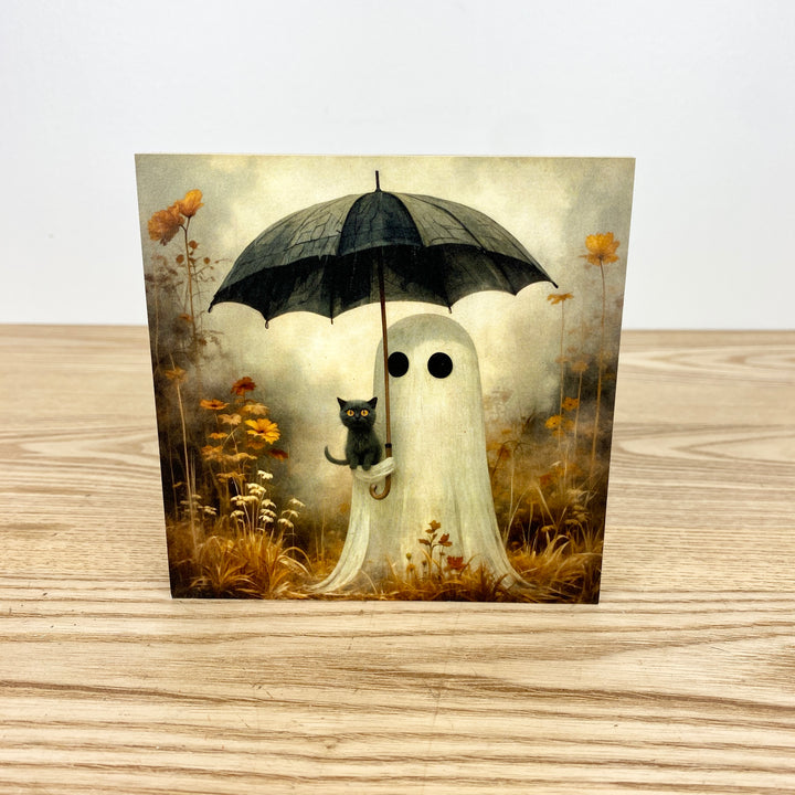 Ghost with an umbrella and a black cat in a field of flowers on a wooden surface